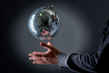 A disco ball levitating above a man's hand, old school party concept