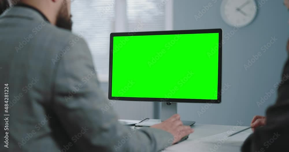 Poster back view of office workers sitting together at desk and using pc with chroma key monitor. two colle
