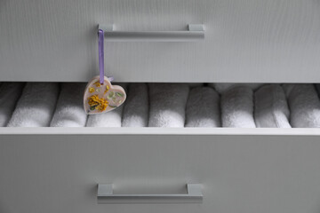 Chest of drawers with heart shaped scented wax sachet and towels, closeup