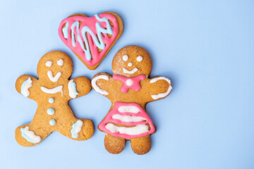 Boy and girl gingerbread couple and heart on the blue background with copy space for St Valentines Day. 
