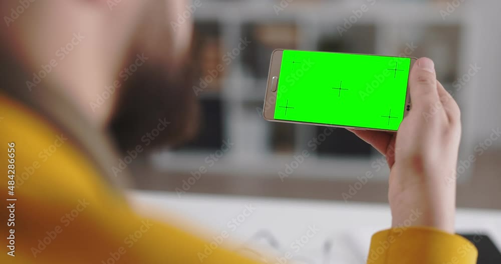 Poster back view of business person holding in hands modern smartphone in horizontal position. focus on gre