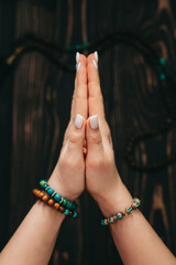 Woman reading mantras or prayers, hands folded in namaste in front of rosary or mala beads strand...