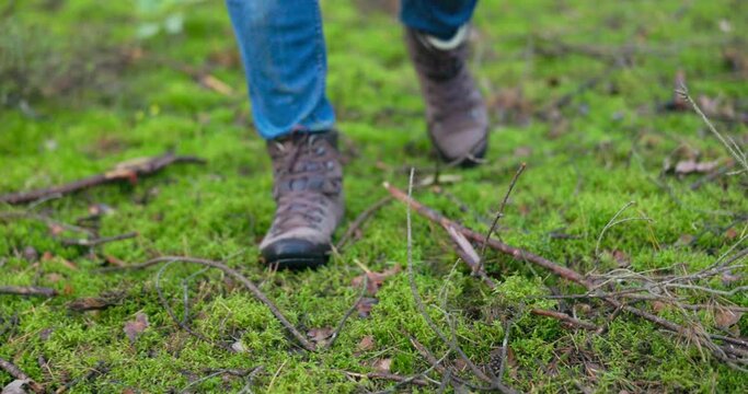Man's feet feet firmly on the ground, trapper boots warm, guy takes steps in the woods, moss, mulch, mushroom walk, spending time outdoors, forest hike