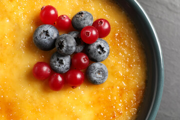 Delicious creme brulee with fresh berries on black table, closeup