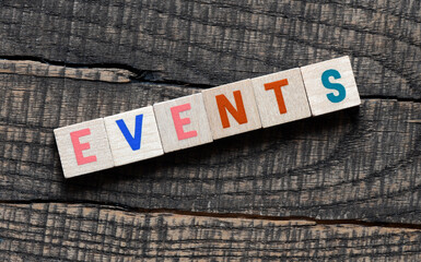 Word EVENTS arranged from wooden letters on a wooden board.
