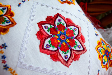 Colorful mandala embroidery design on white linen pillow.