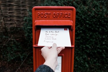 hand posting a letter through an English red post box