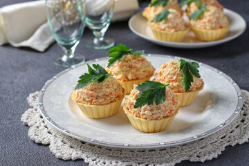 Tartlets with cheese, chicken and carrots garnished with parsley on a gray background