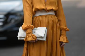 woman wearing orange dress and white handbag