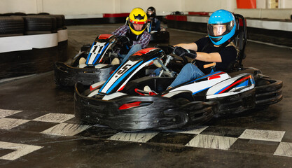 Young people driving sport cars for karting in a circuit lap in sport club
