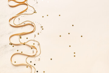 Golden ribbon and beads with confetti on light background