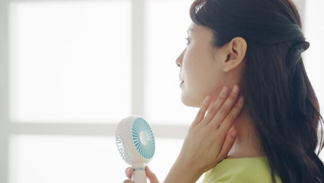 ハンディファンを使う女性　ポータブル扇風機