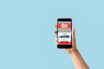 Female hand and mobile phone with open car rent app on blue background