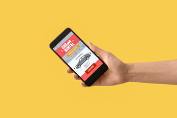Female hand and mobile phone with open car rent app on yellow background