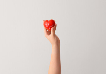 Woman holding red heart with cardiogram drawing on color background, closeup. Donation concept