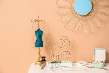 Stylish jewelry on chest of drawers and mirror on color wall