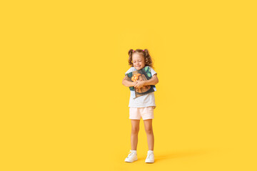 Adorable little girl with book on yellow background