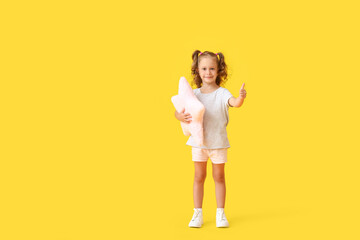 Fototapeta na wymiar Adorable little girl with pillow in shape of star on yellow background