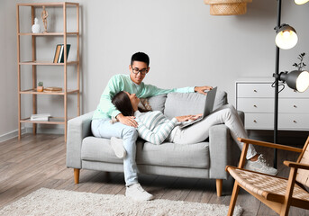 Fototapeta premium Young man and his wife with laptop shopping online on sofa at home