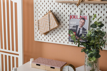 Pegboard with magazine and books hanging on beige wall