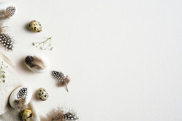 Obraz premium Elegant Easter flatlay composition. Stylish Easter eggs decorated feathers with gypsophila flowers on white table. Flat lay, top view, copy space.