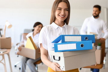 Young woman holding box with folders in office on moving day