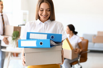 Young woman holding box with folders in office on moving day