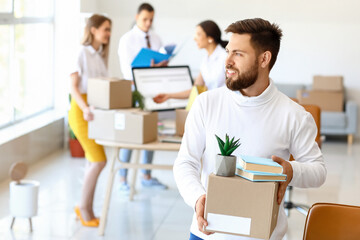 Fototapeta na wymiar Handsome man holding box with things in office on moving day