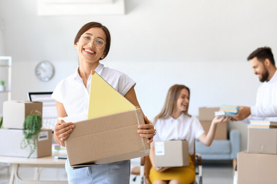 Beautiful woman holding box with things in office on moving day