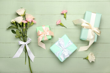 Beautiful gift boxes with flowers on green wooden background