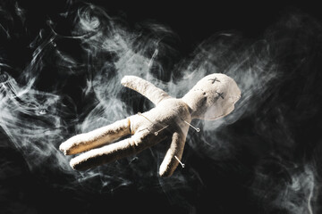 Voodoo doll with pins and smoke on dark background