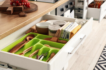 Opened drawers with kitchen utensils in room