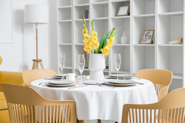 Beautiful table setting and vase with Gladiolus flowers in dining room