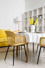 Table with beautiful setting and Gladiolus flowers in modern room