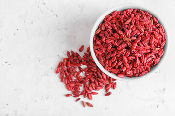 Bowl with dried barberries on light background