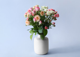 Vase with bouquet of beautiful fresh roses on light background