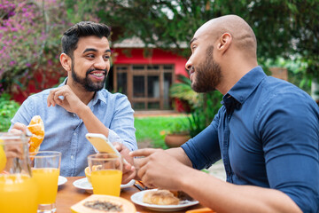 african american couple having breakfast and talking outside in the garden