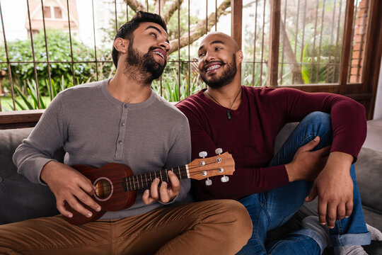 black gay couple playing music and singing in the sofa