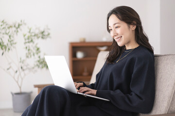 ソファーでノートパソコンを操作する女性