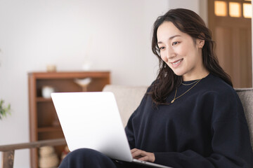 ソファーでノートパソコンを操作する女性