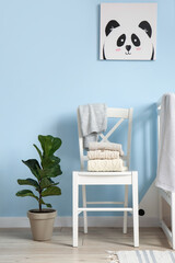 Obraz premium Children's sweaters on white chair near color wall