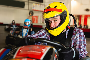 Portrait of nice man driving racing car at kart circuit