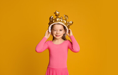 Cute girl in inflatable crown on yellow background. Little princess