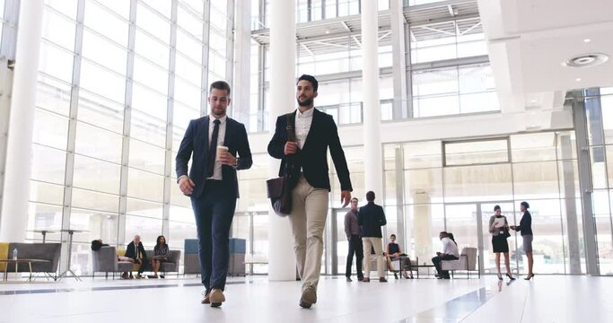 Two young businessmen arriving to work together in the morning.