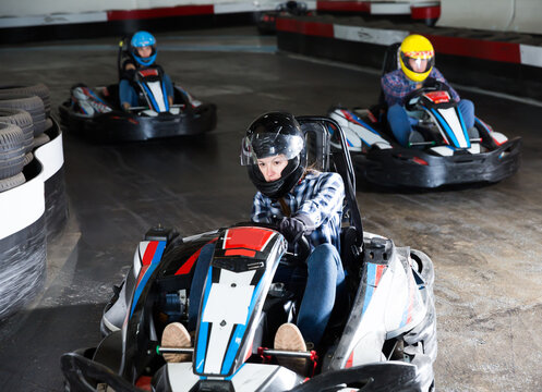 Adult people in helmets driving cars for karting in sport club indoor