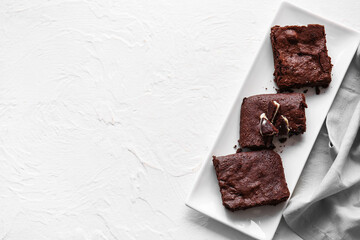 Plate with pieces of tasty chocolate brownie on white background