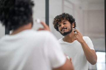Pleased concentrated young male preparing for shaving