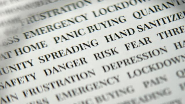 White paper with black text on it looked at through a loupe. Magnifying glass coming into the shot from the right. Defocused. Selective focus. Blurred. Covid related words.