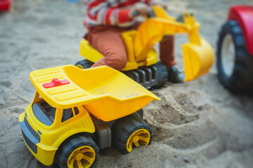 Children playing in the sandbox sandpit, kids with toy car vehicle, playground in kindergarten day...