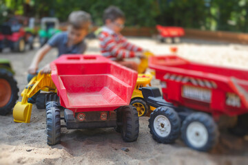 Children playing in the sandbox sandpit, kids with toy car vehicle, playground in kindergarten day...